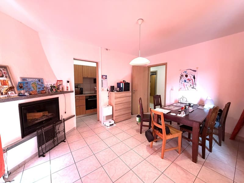 Dining room with a fireplace, dining table, chairs, wooden cabinet, and a kitchen entrance