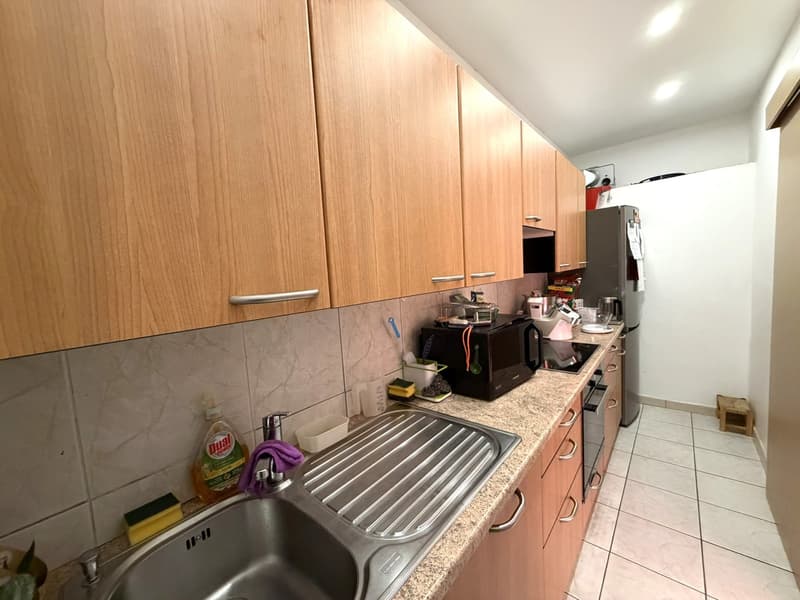 modern kitchen with wooden cabinets, stainless steel sink, dishwasher, microwave, refrigerator, countertop, tiled floor