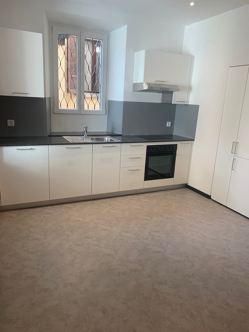 modern kitchen, white cabinets, black countertops, stainless steel sink, oven, extractor hood, electrical outlets, tiled floor