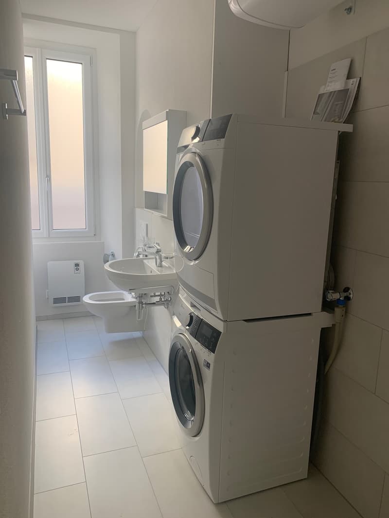 white tiled floor, white sink, white toilet, washing machine, dryer, radiator