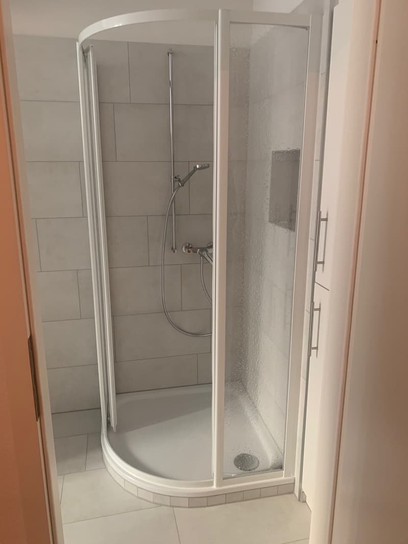 shower cubicle, tiled walls, glass door, shower head, drain