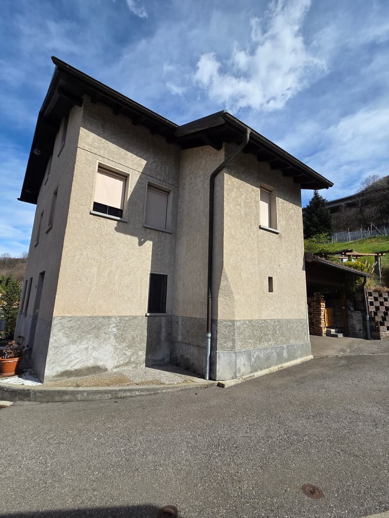 2 story house, beige exterior, black roof, windows with white shutters, small garden, paved driveway