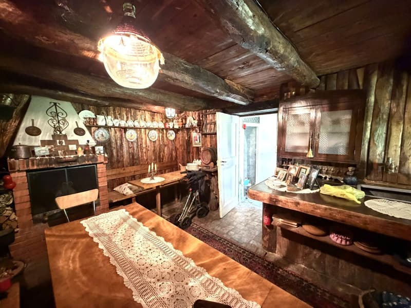 wooden walls, fireplace, dining table, chairs, wooden cabinets, chandelier, shelves with plates and items