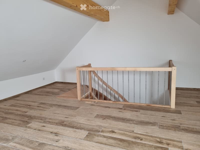 Wooden floor, white walls, wooden staircase, metal railings, light switches on the wall