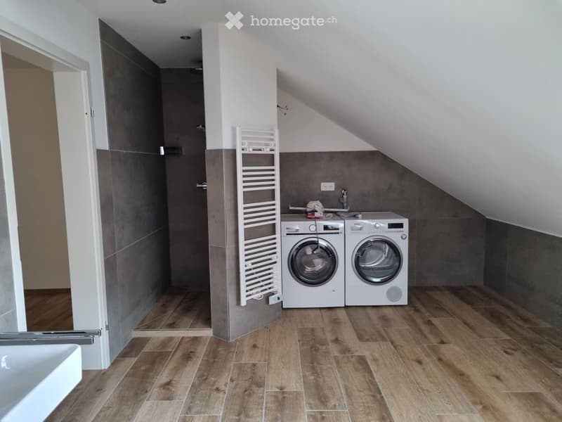 wooden floor, tiled walls, washing machines, drying rack, white sink, shower space