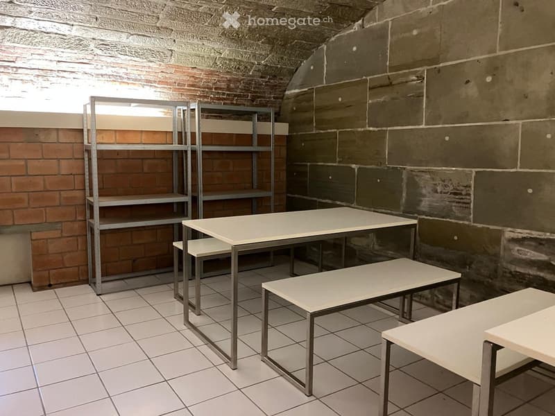 Storage room, brick walls, tiled floor, metal shelving units, benches, desk