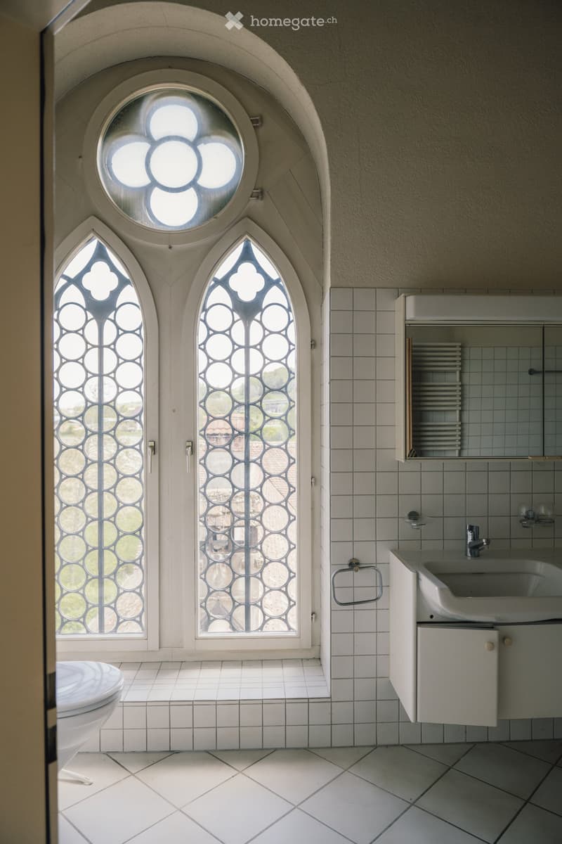 white tiled floor, white tiled walls, white sink, white toilet, arched window, mirror