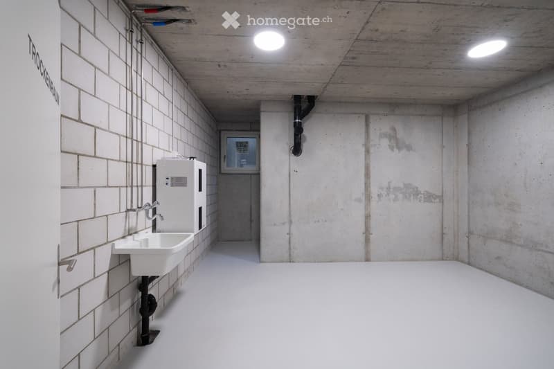 small room, concrete wall, white sink, white floor, pipe on wall