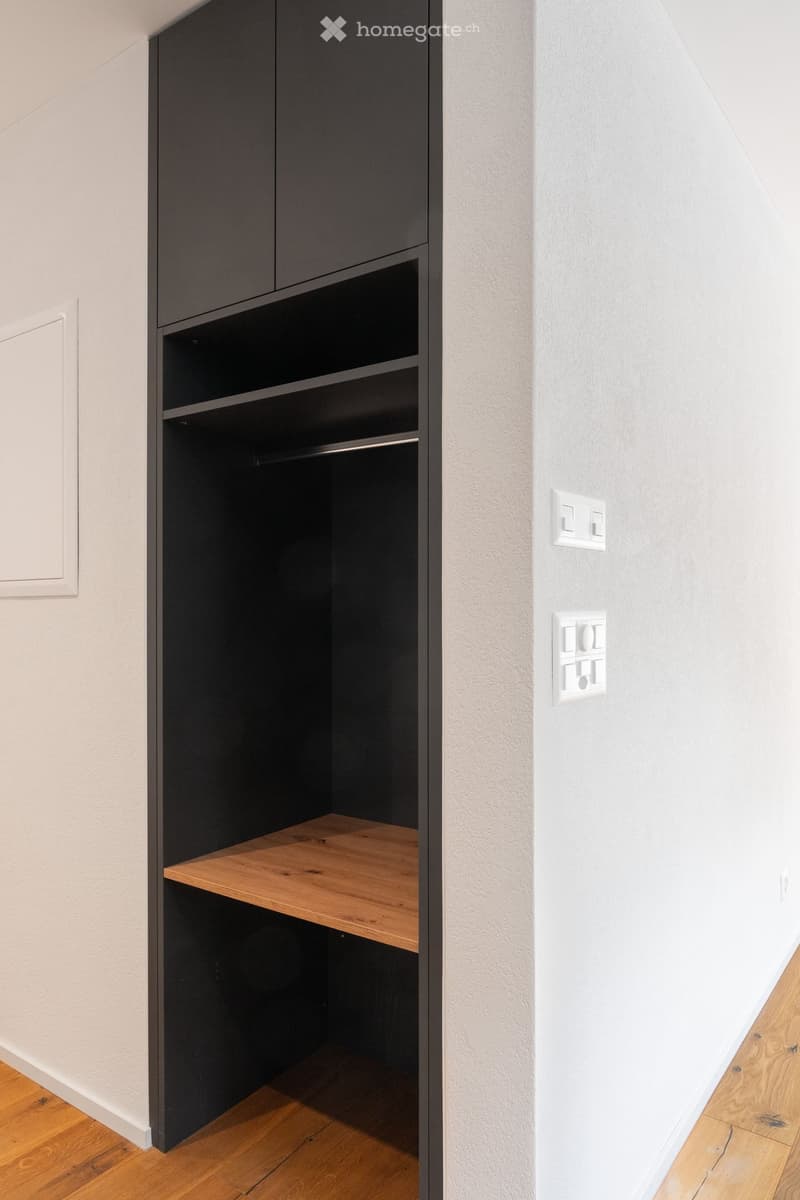 wooden shelf, white wall, black built-in closet, power outlets