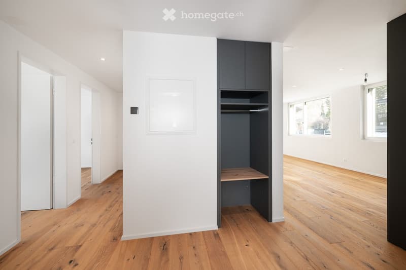 Minimalist room with built-in wardrobe, wooden floors, white walls, and an empty shelf inside the wardrobe