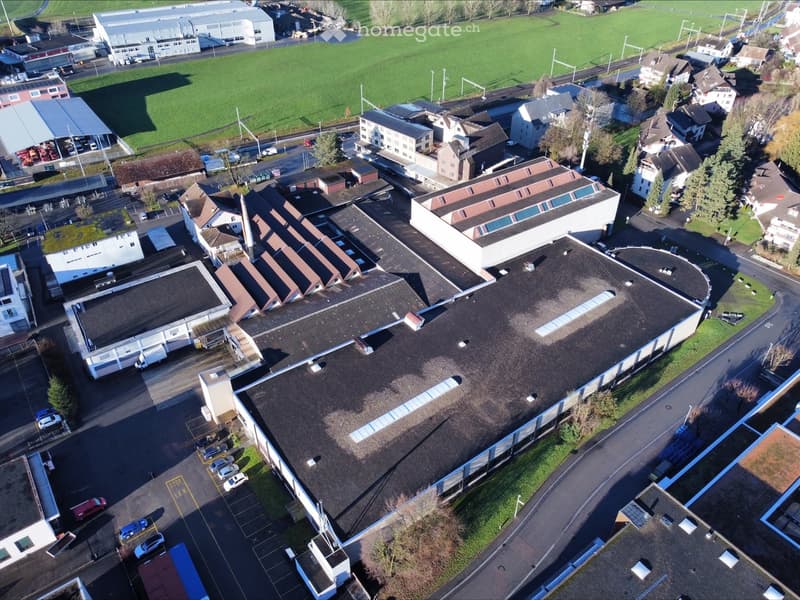 Industrial building with multiple levels, several car parking areas, and a wide area of grass