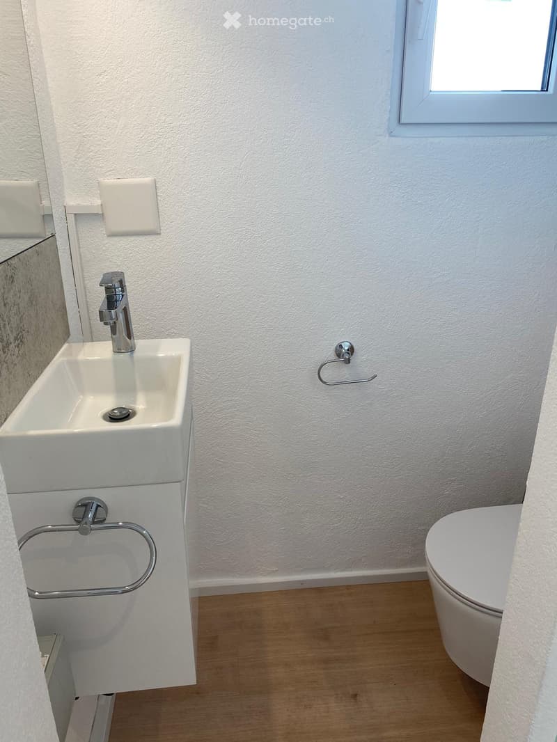 A compact and clean bathroom with a sink, a toilet, and a towel rack.