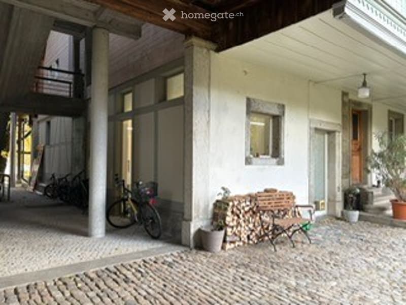 cobblestone street, building with wooden ceiling, bicycle parked, wooden bench, firewood, lamp