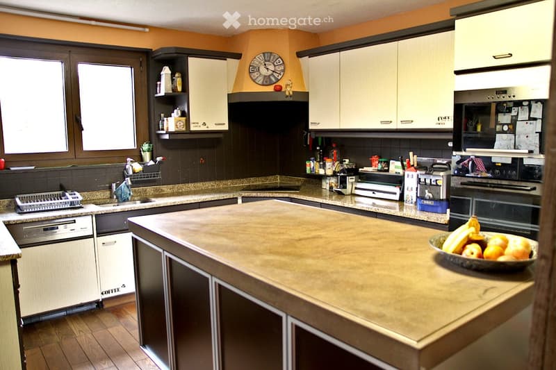 granite countertops, L-shaped kitchen island, dishwasher, two ovens, wooden floor, open windows, wall clock