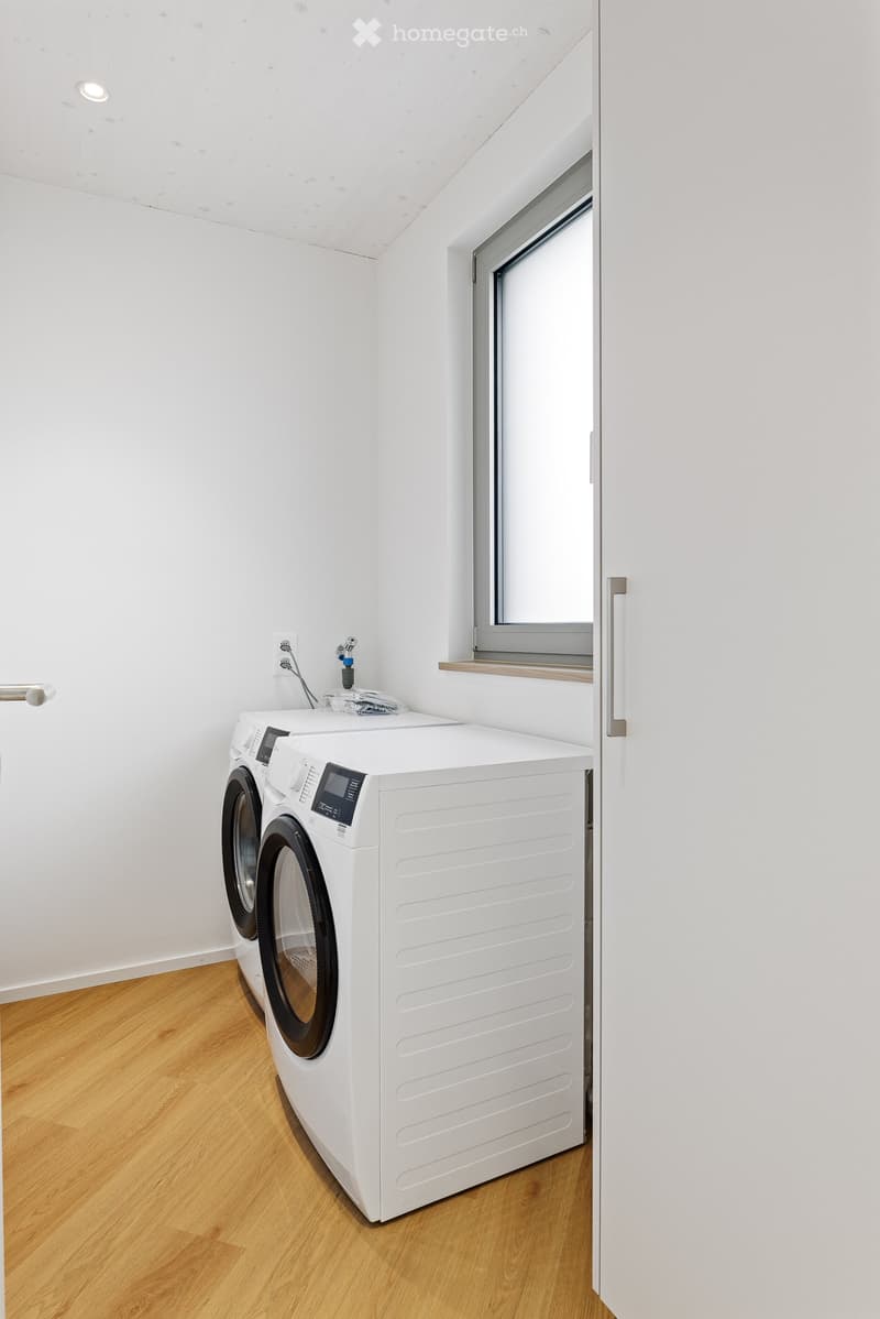 A small laundry room with a white washing machine and dryer, a faucet, and an outlet.