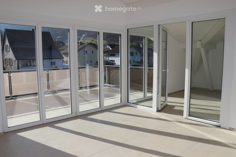 sliding glass doors leading to balcony, large windows, white walls, tiled floor, balcony with railings