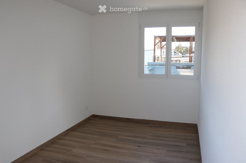 empty room with white walls, wooden floor, single window with exterior view