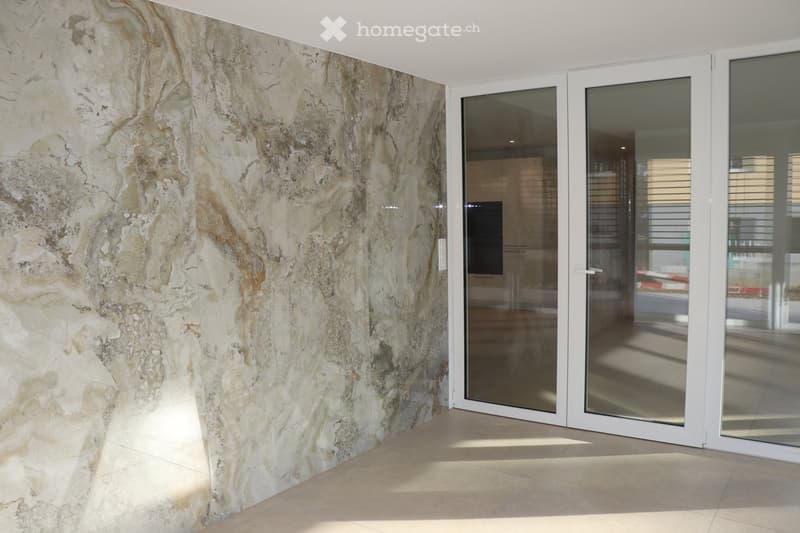 Large marble-like wall, glass sliding doors, tiled floor