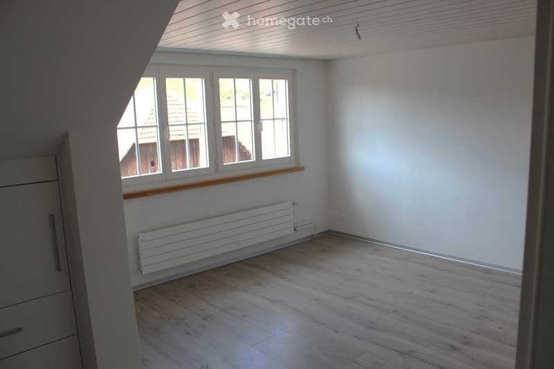 Empty room with wooden floor, radiator, window and wooden window sill.