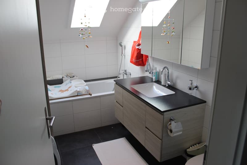modern bathroom with bathtub, sink, mirror, cabinets, dark floor tiles, bright walls