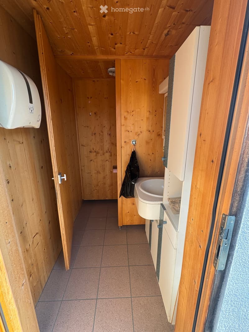 wooden walls, tiled floor, a sink, a trash bin, a towel rack, paper towel dispenser