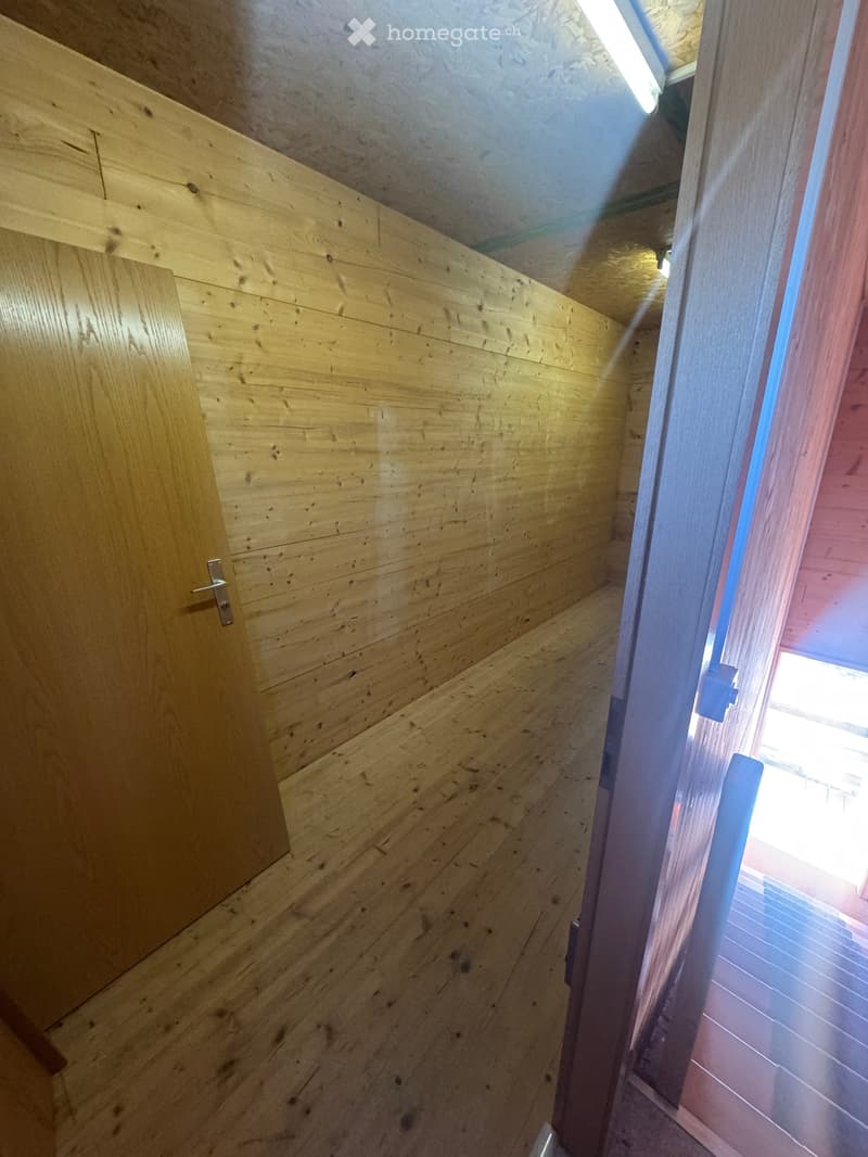 Empty wooden hallway with natural light coming through a frosted glass door at the end.