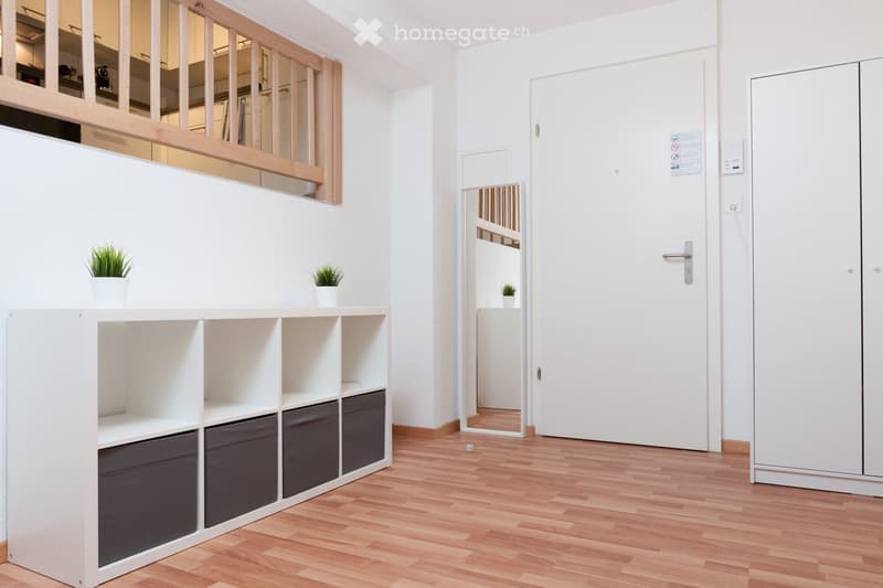 Empty room with a white shelving unit, wooden floor, and white walls.
