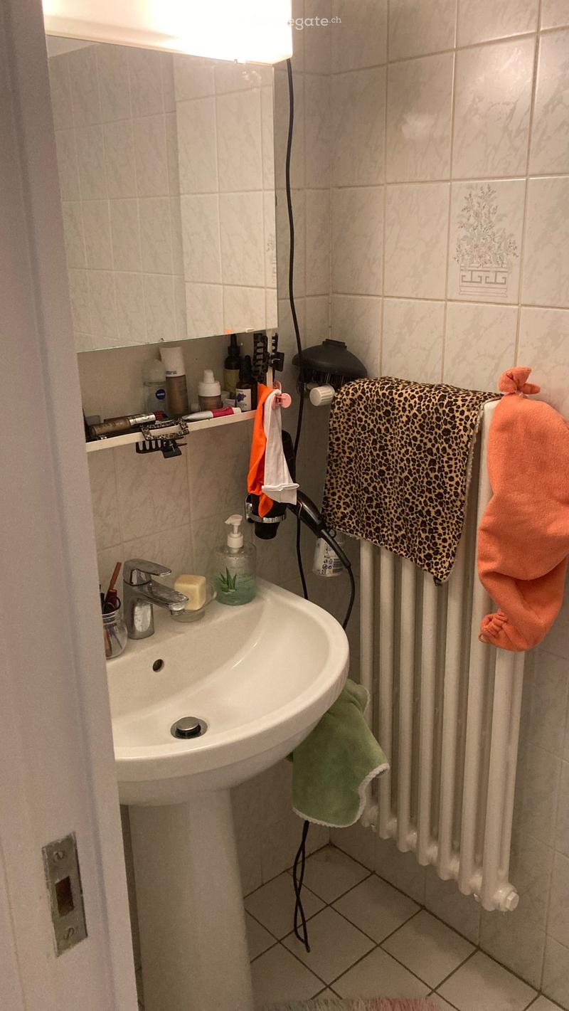 White sink, white tiles, mirror, towel, clothes dryer