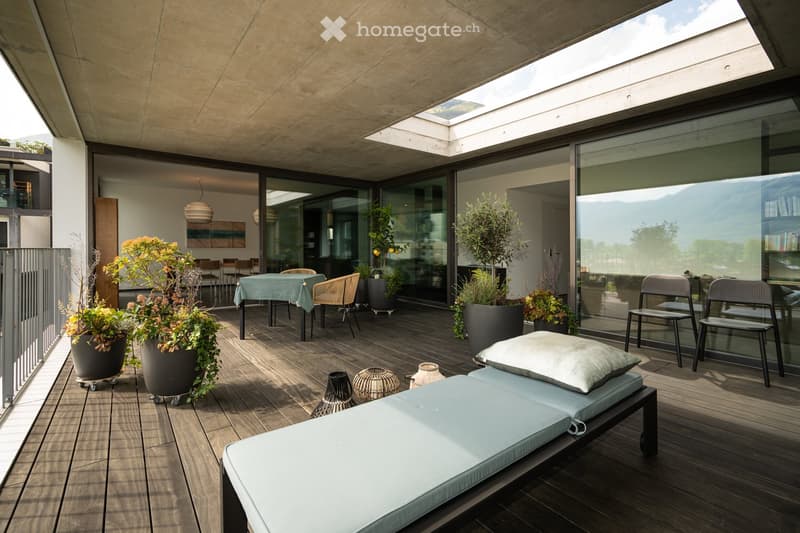 wooden floor, outdoor table and chairs, lounge bed, potted plants, glass walls, skylight