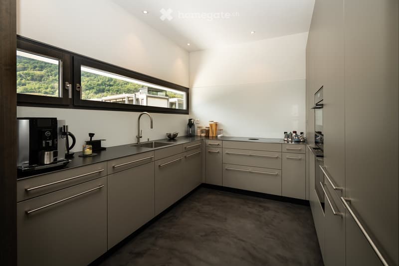 modern kitchen with gray cabinets, black countertops, stainless steel sink, faucet, coffee machine, large windows