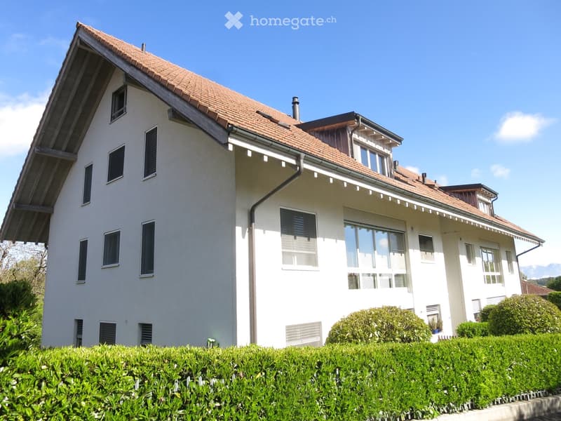 3-story white house, red tiled roof, multiple windows, chimney, plants and bushes