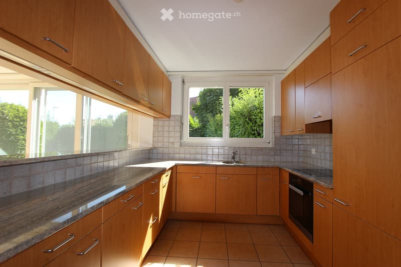 kitchen with wooden cabinets, granite countertop, large windows, stainless steel appliances