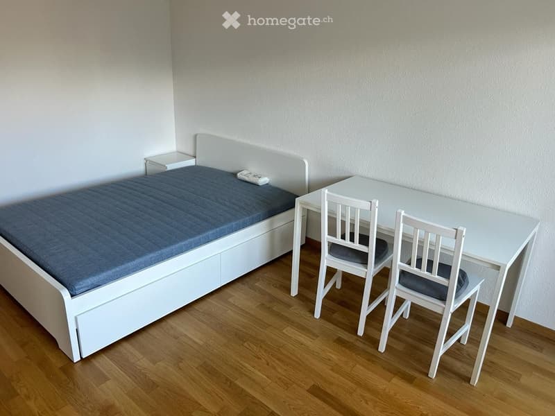 white bed with a blue mattress, white nightstands, white desk with two chairs, wooden floor