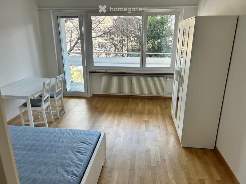 bedroom with bed, wardrobe, desk, chair, windows with balcony, wooden floor