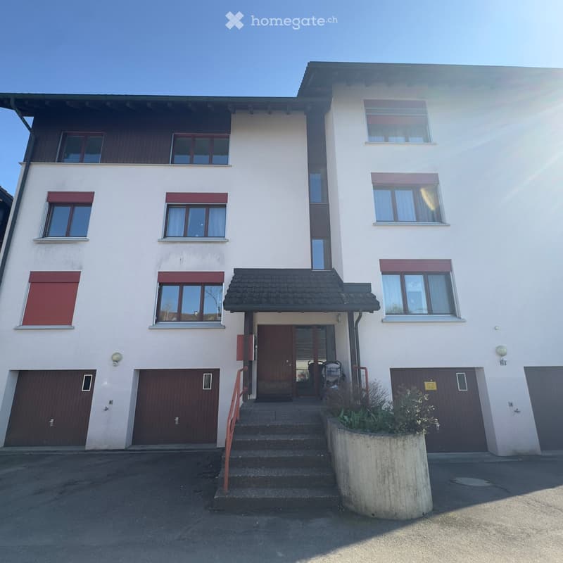 3 story house, white exterior, brown garage doors, 3 windows on each floor, steps leading to the entrance