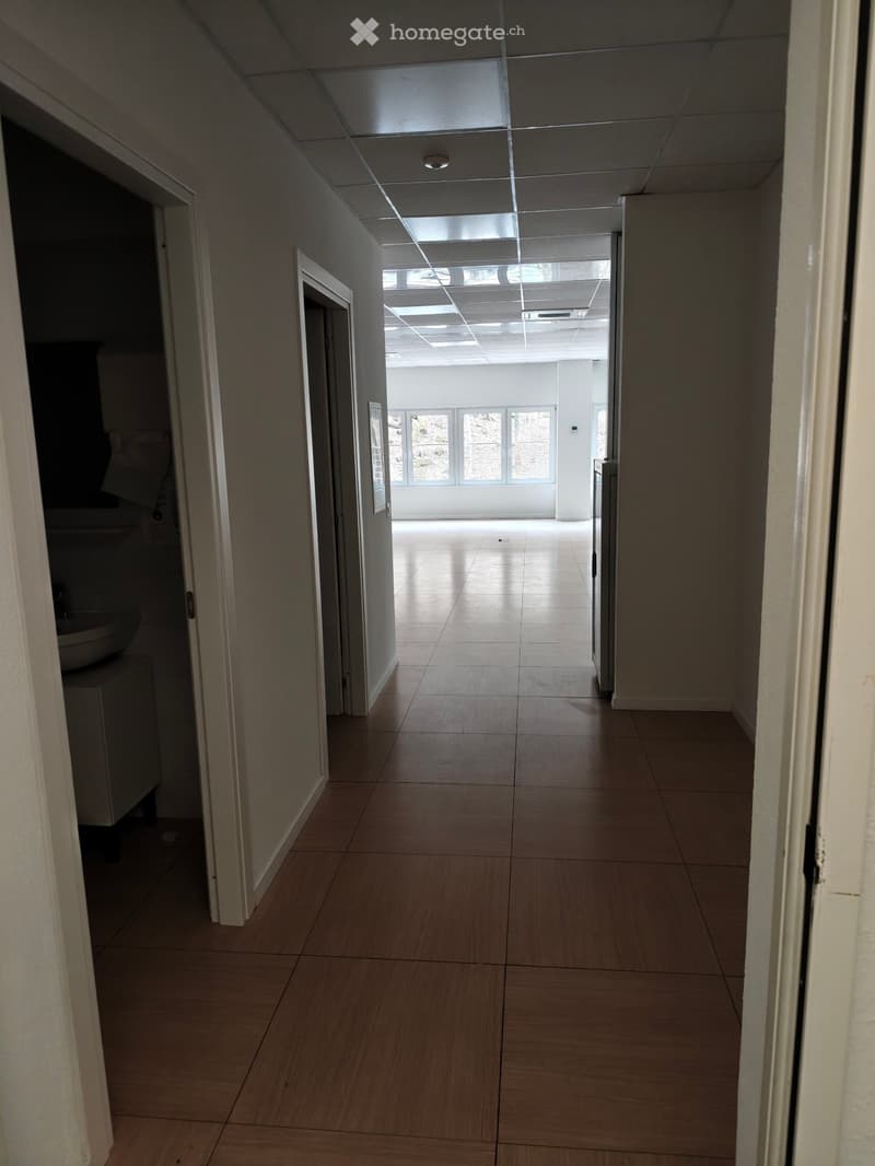 Empty hallway with tiled floor, white walls, and ceiling lights
