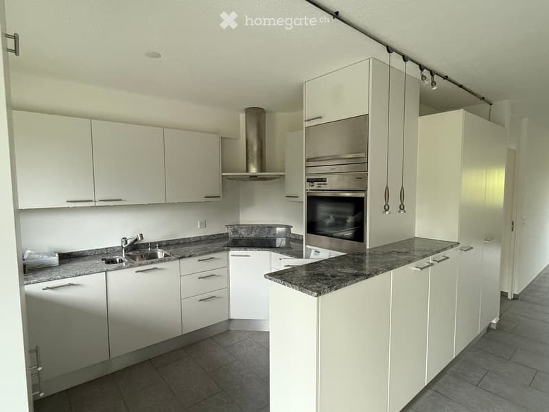 modern kitchen with white cabinets, granite countertops, stainless steel appliances, under-cabinet lighting, and a sink with a faucet