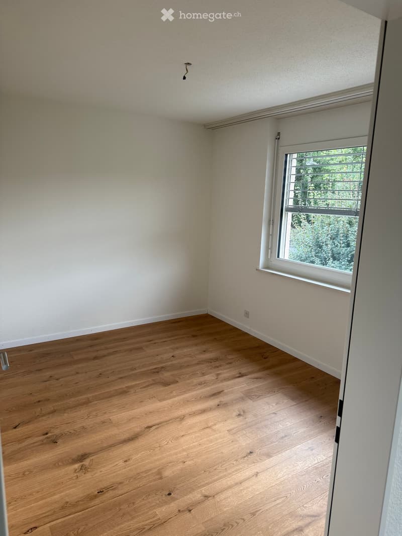 empty room, wooden floor, white walls, window with blinds, power outlet