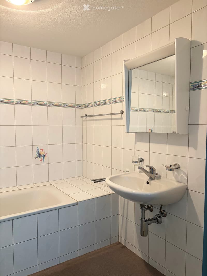 Bathroom with white tiles, bathtub, sink, mirror, towel rack, and faucet