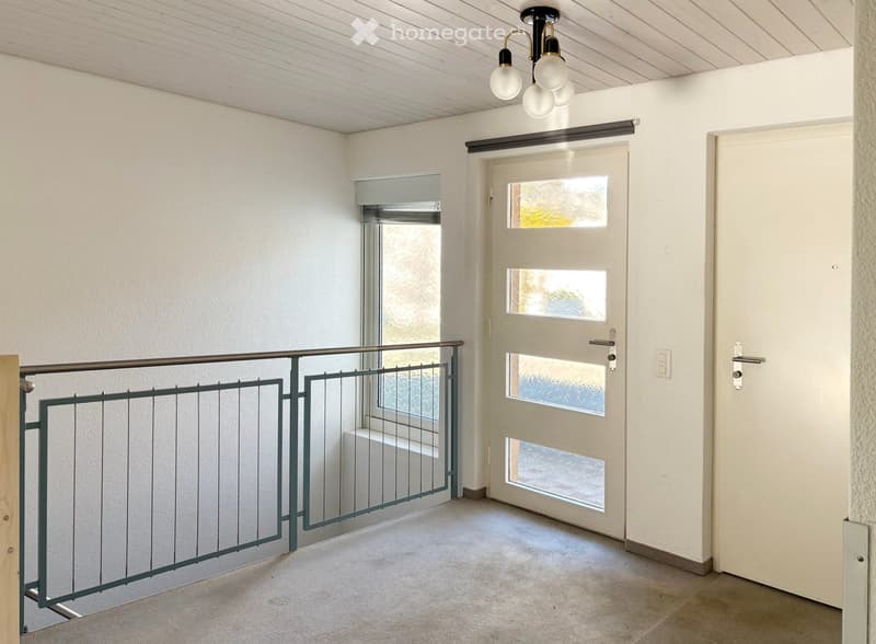 Empty room with white walls, white ceiling, white door, window with metal railing, metal railing on the left side
