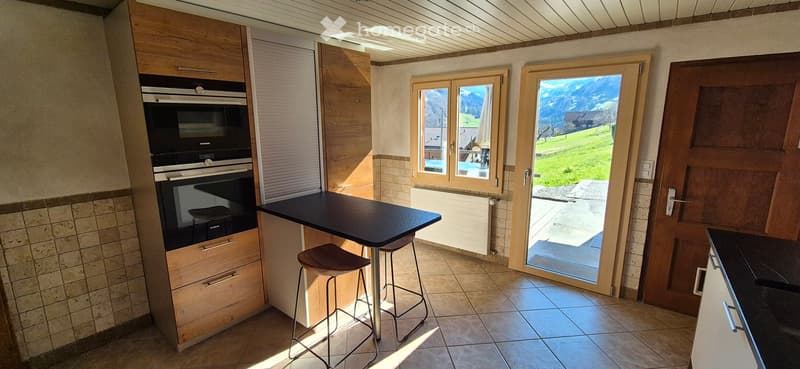 kitchen with oven, table, chairs, tiled floor, sliding door, view of mountains