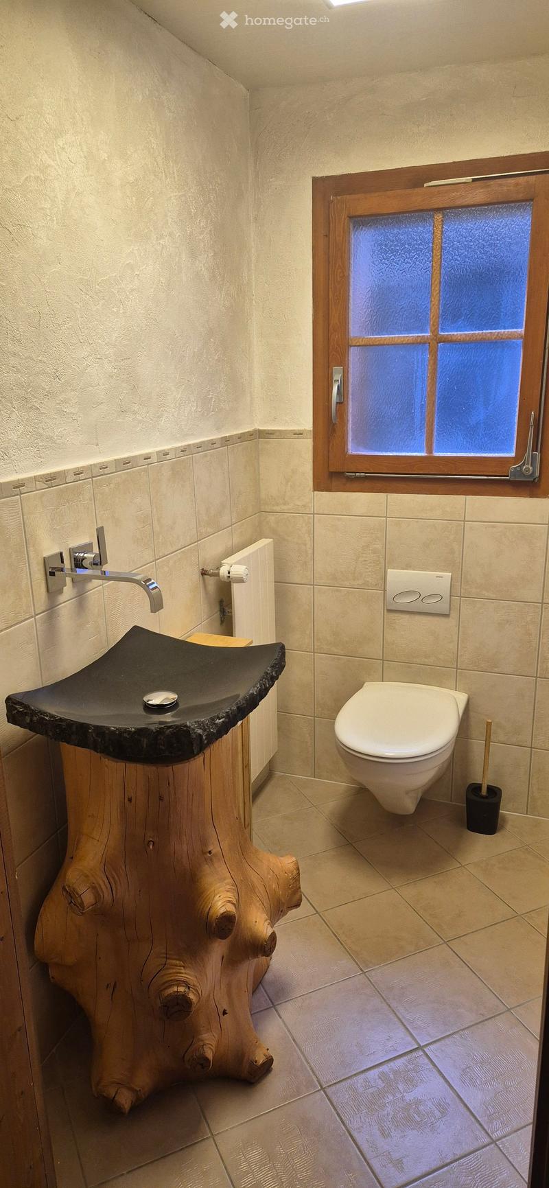 Bathroom with a wooden sink, white toilet, wooden window frame, tiled floor, and a radiator.