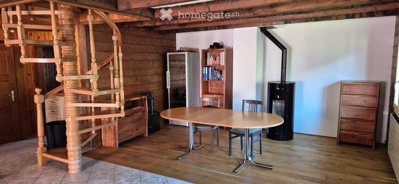 wooden spiral staircase, round table, chairs, wooden shelves, books, fireplace, radiator