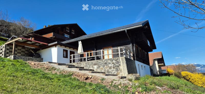 2 story house, raised ground floor, wooden exterior, balcony, solar panels on roof