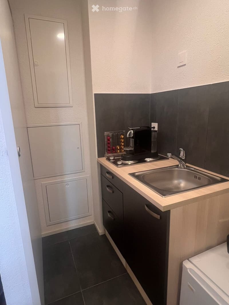 small kitchen with sink, stove, coffee machine, cabinets, washing machine