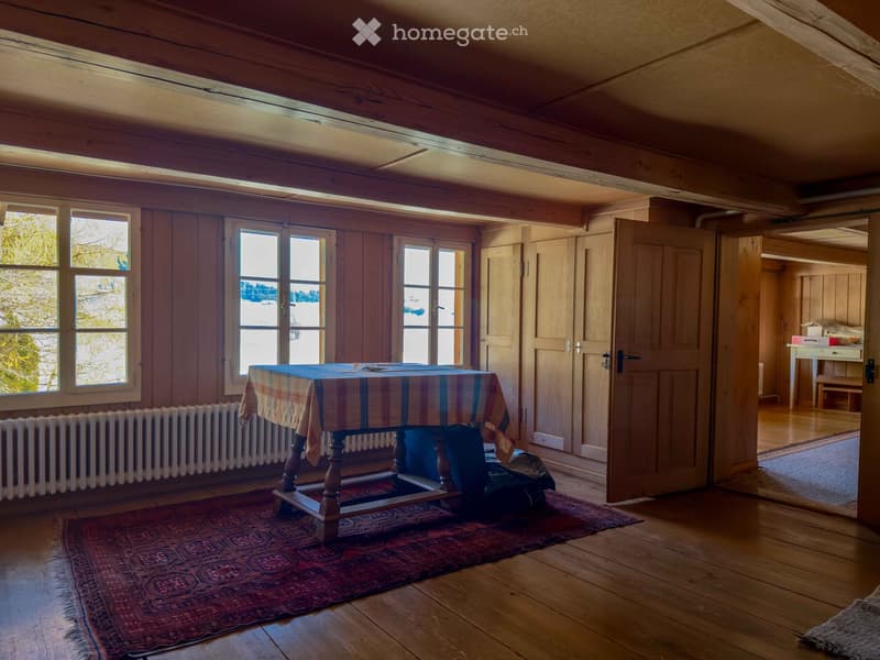 wooden floor, wooden walls, large windows, table with tablecloth, radiator, rug, open door