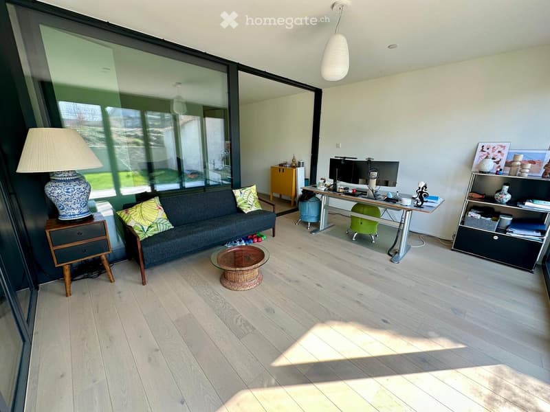 modern living room with large windows, hardwood floors, couch, desk, lamp, shelves, and a view of the outside