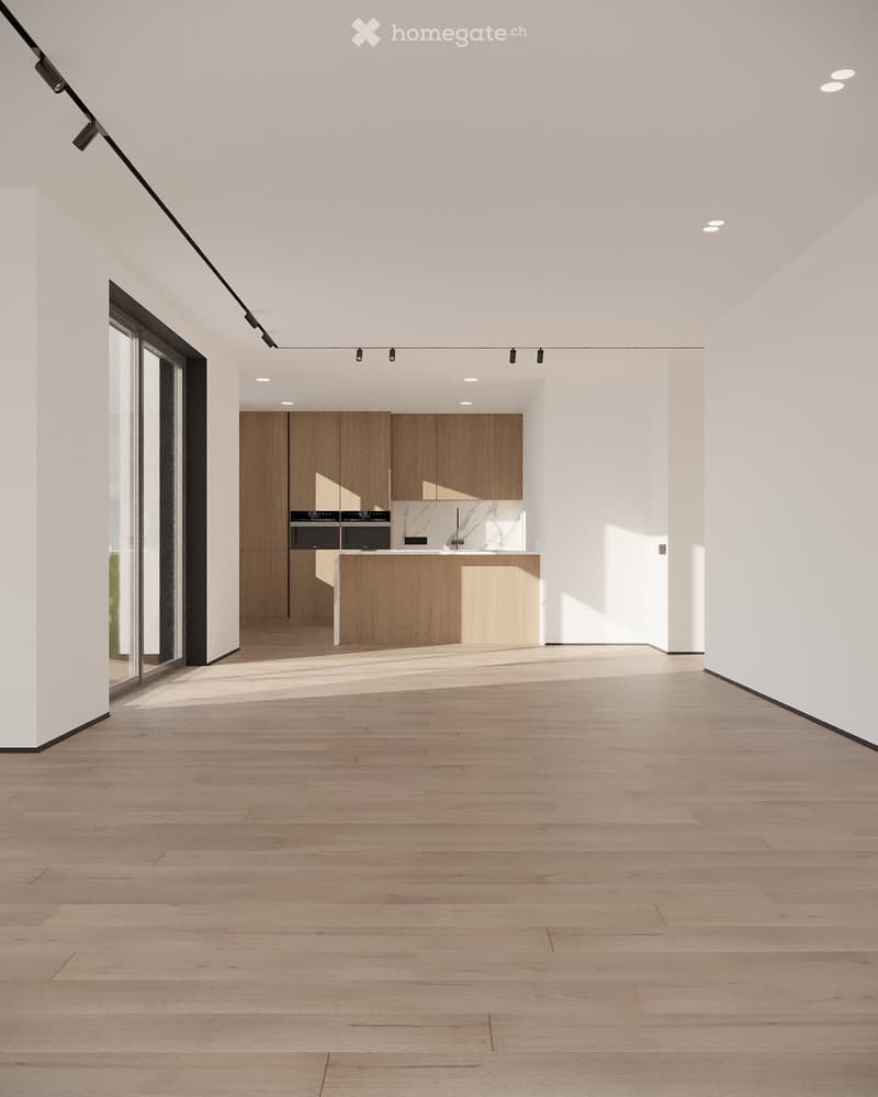Empty room with light wooden flooring, white walls, and a modern kitchen area in the background featuring wooden cabinets and stainless steel appliances.