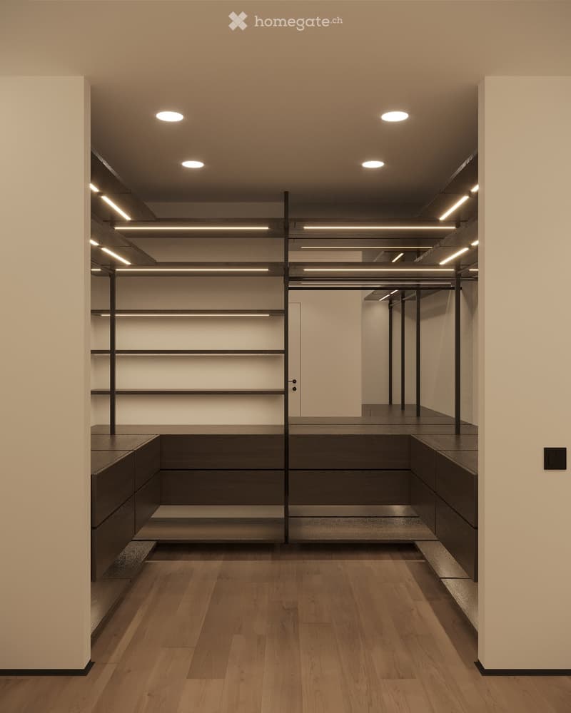 Modern, minimalist unfurnished room with wooden flooring, built-in shelving units, and recessed lighting. The space features a central island with built-in seating and storage, flanked by sleek, dark wooden cabinetry.