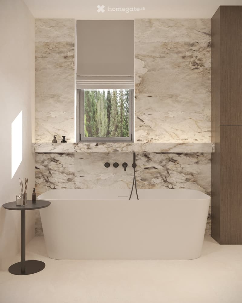 Bathroom with marble walls, white bathtub, black faucet, small table with glass and bottles, wooden cabinet, window with trees view